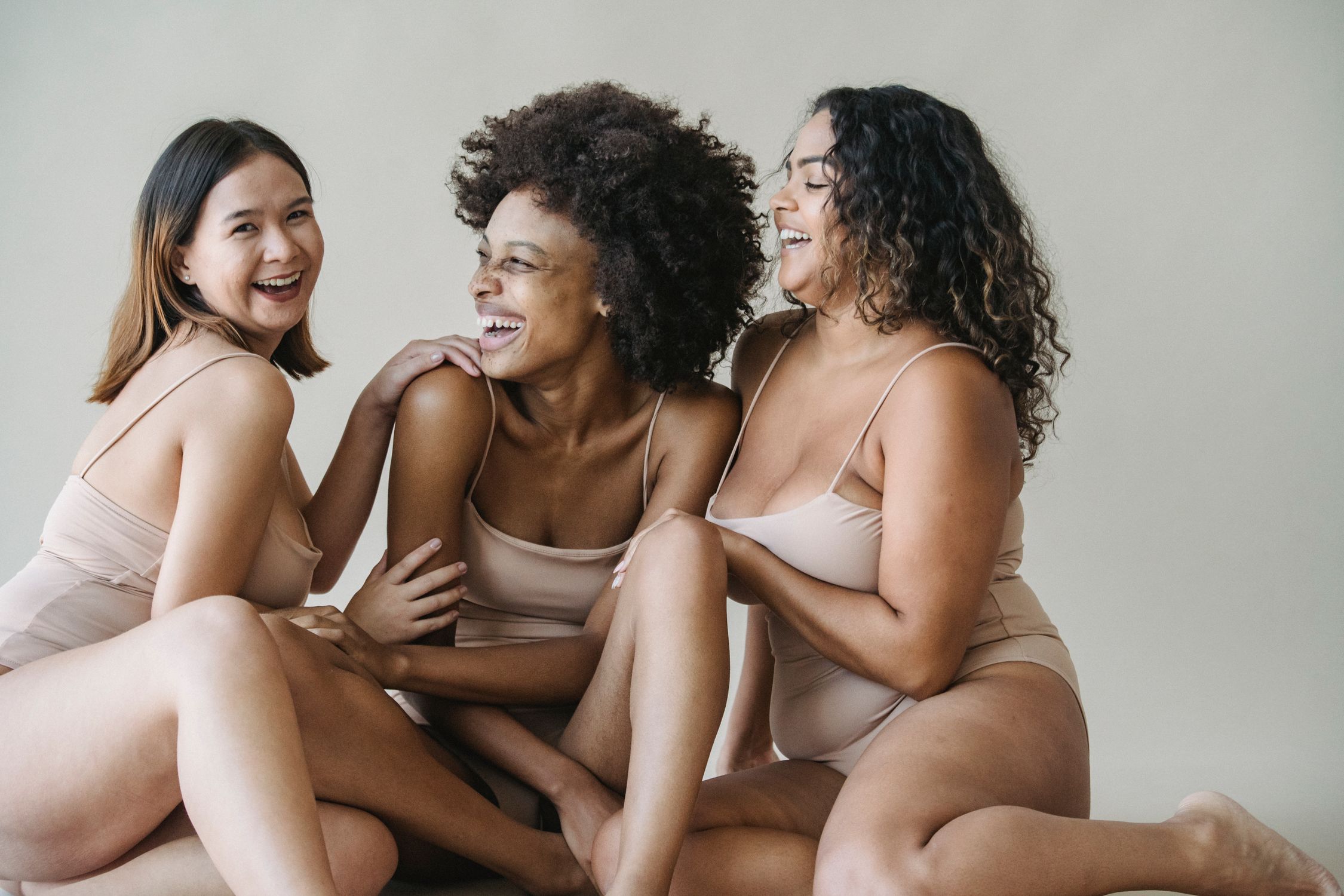 Three women of different body types wearing lingerie in a studio.